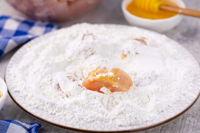 Tossing chicken pieces in flour and cornstarch mix.