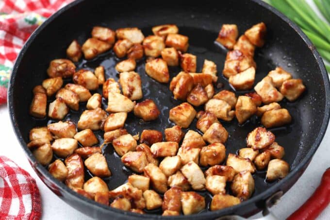Searing chicken pieces in a skillet.