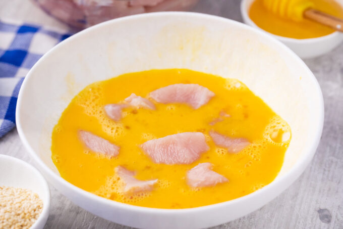 Dipping chicken pieces in beaten eggs.