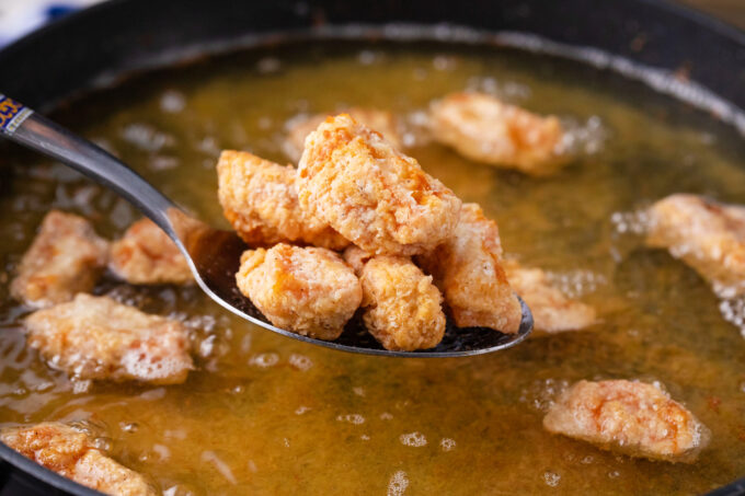 Frying chicken pieces in oil.