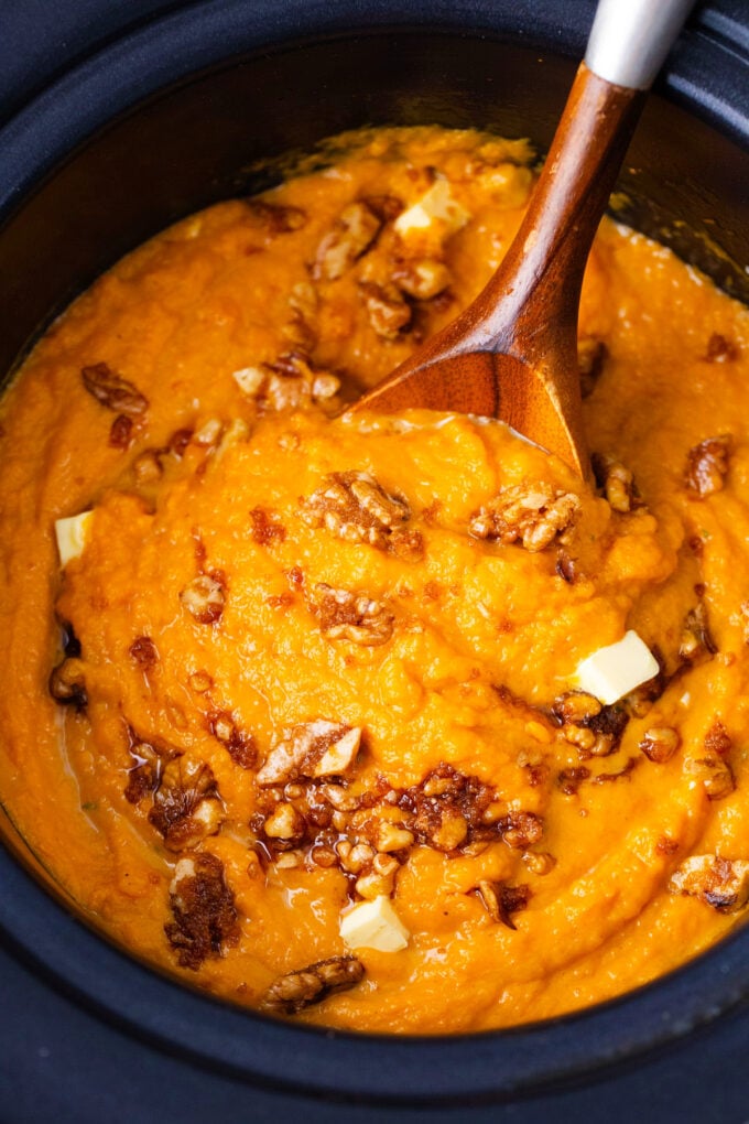 Crockpot mashed sweet potatoes topped with nuts.