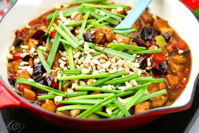 Making Kung Pao Chicken with veggies, green onions, and peanuts.