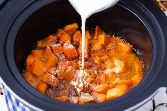 Adding cream to crockpot mashed sweet potatoes.