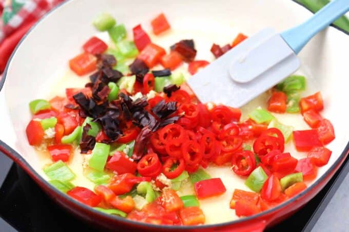 Stir frying bell pepper and chili peppers in a pan.