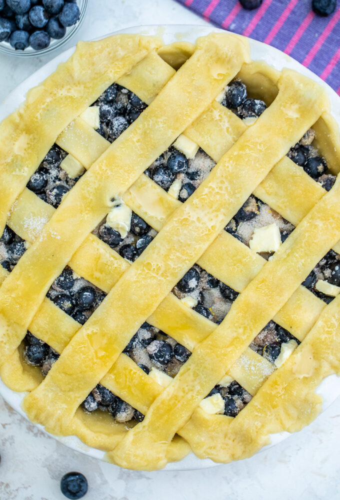 unbaked Blueberry Pie with a lattice top and pieces of cold butter