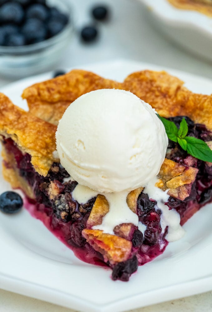 a slice of golden homemade Blueberry Pie topped with ice cream