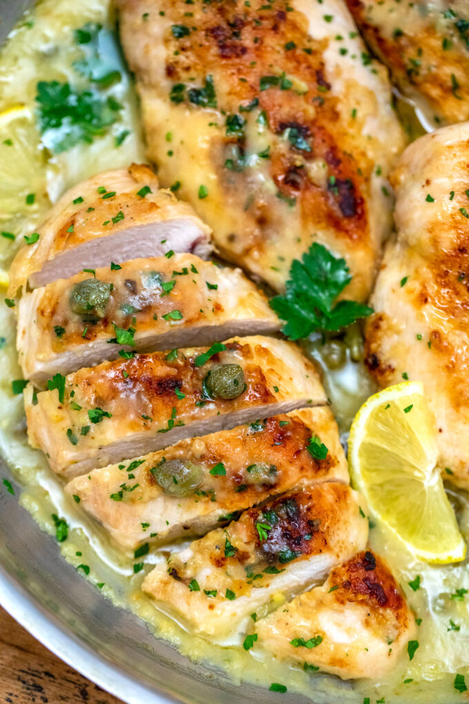 picture of chicken piccata breasts in a creamy lemon garlic sauce garnished with sliced lemon and chopped parsley