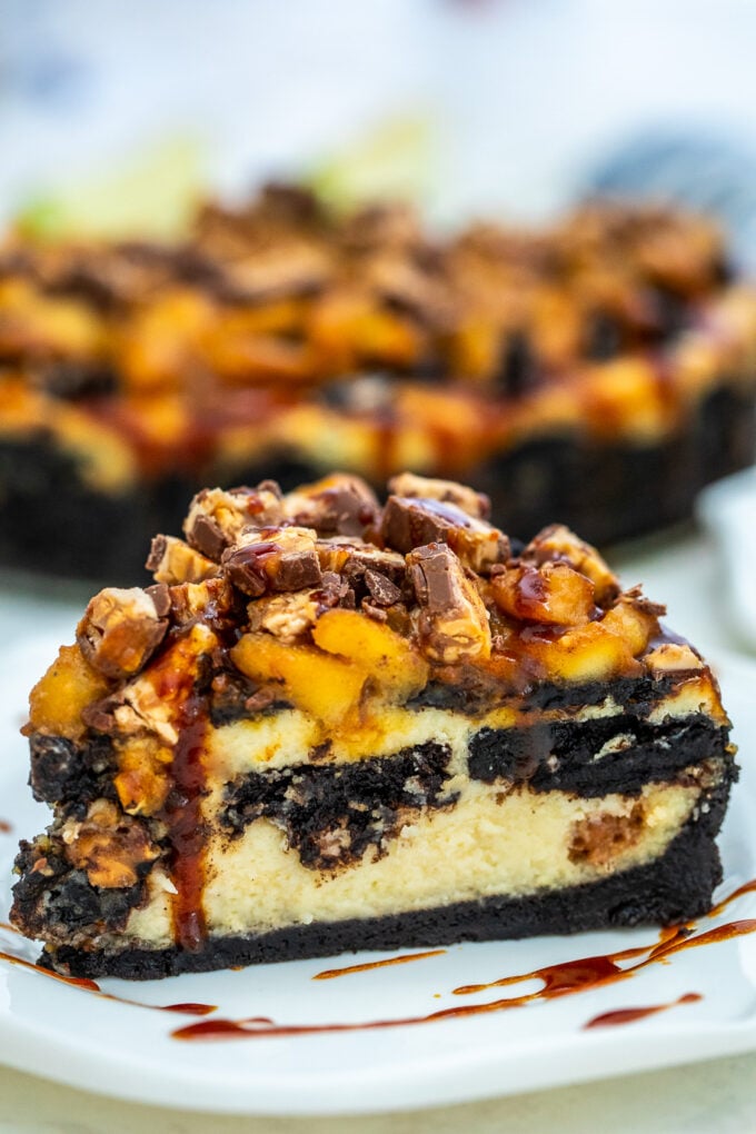 Apple Snickers Cheesecake is not your ordinary dessert! It has your favorite chocolate bar and fruit rolled into one unique and unforgettable cheesecake! #cheesecake #snickers #appledesserts #sweetandsavorymeals #halloweenrecipes