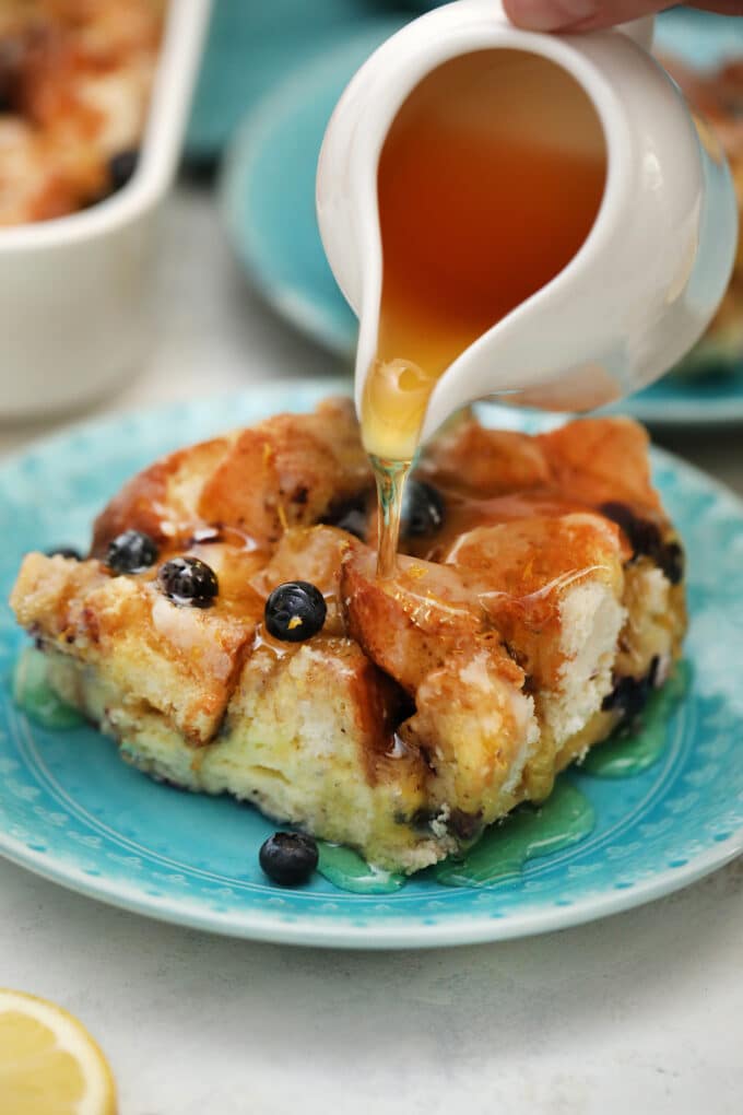 pouring honey over blueberry french toast casserole