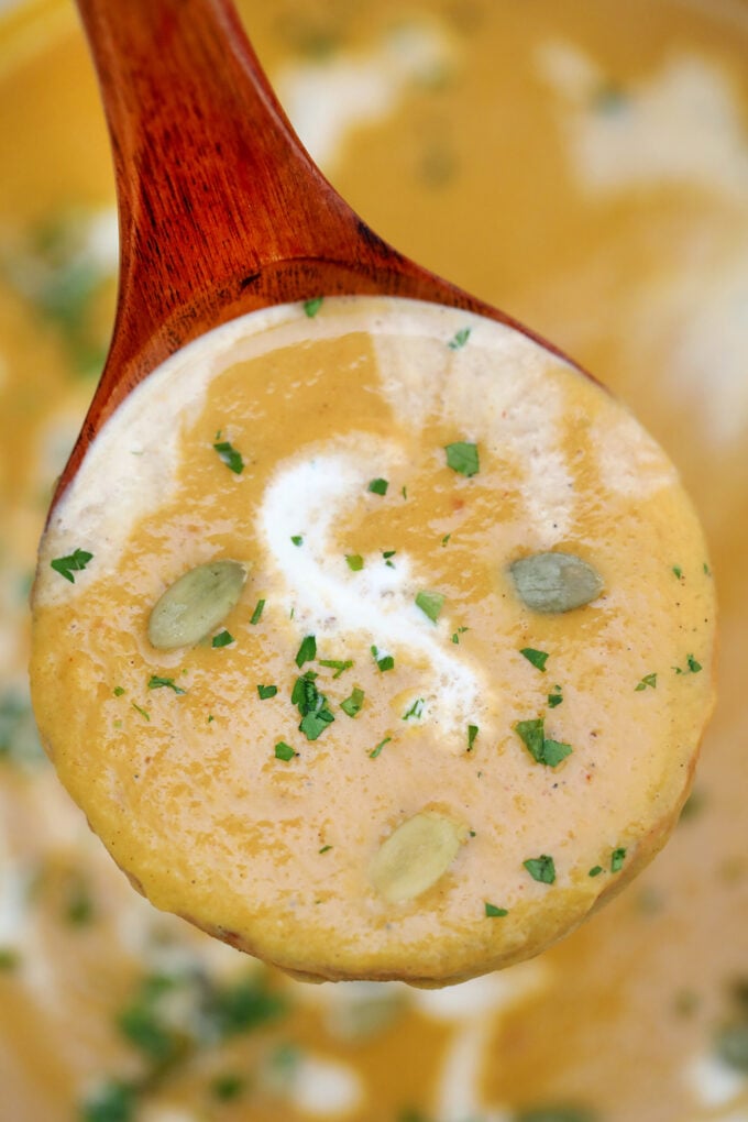 A spoonful of pumpkin soup garnished with pumpkin seeds 