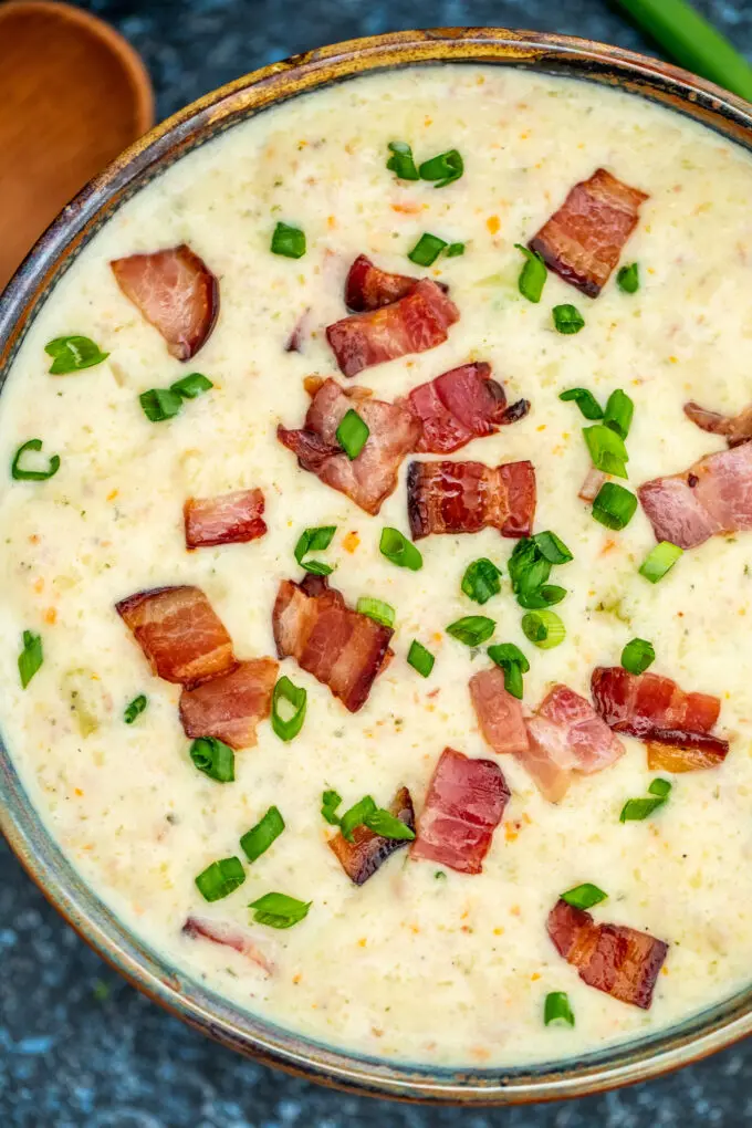 crockpot ham and potato soup in a bowl topped with crispy bacon and chopped green onion