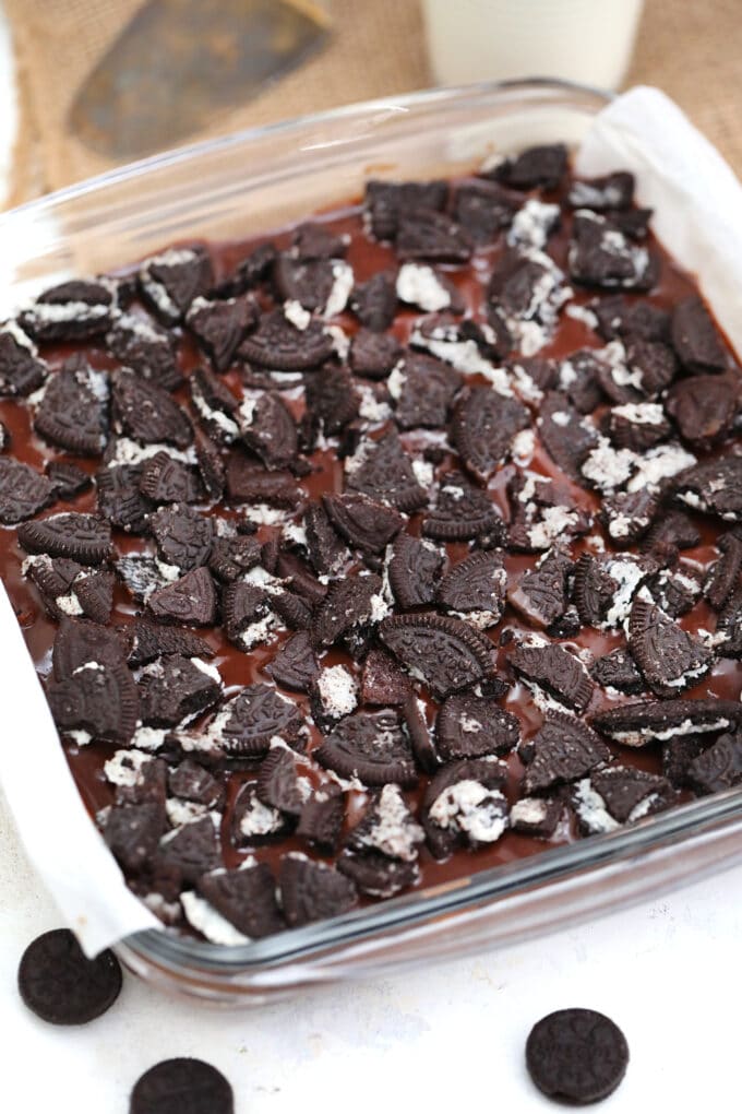 a baking dish with brownie batter topped. with chopped oreos