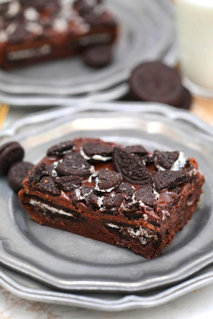 a slice of oreo brownies stuffed with whole oreos and topped with chopped oreos