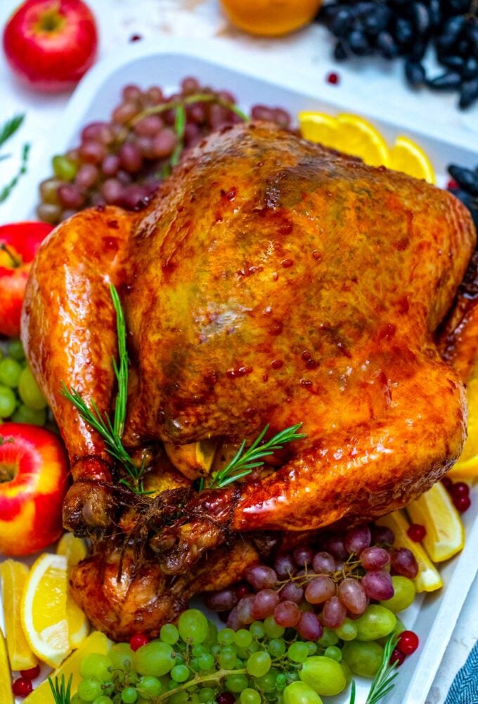 golden brown and crispy oven roasted turkey on a serving platter with fruits and lemon