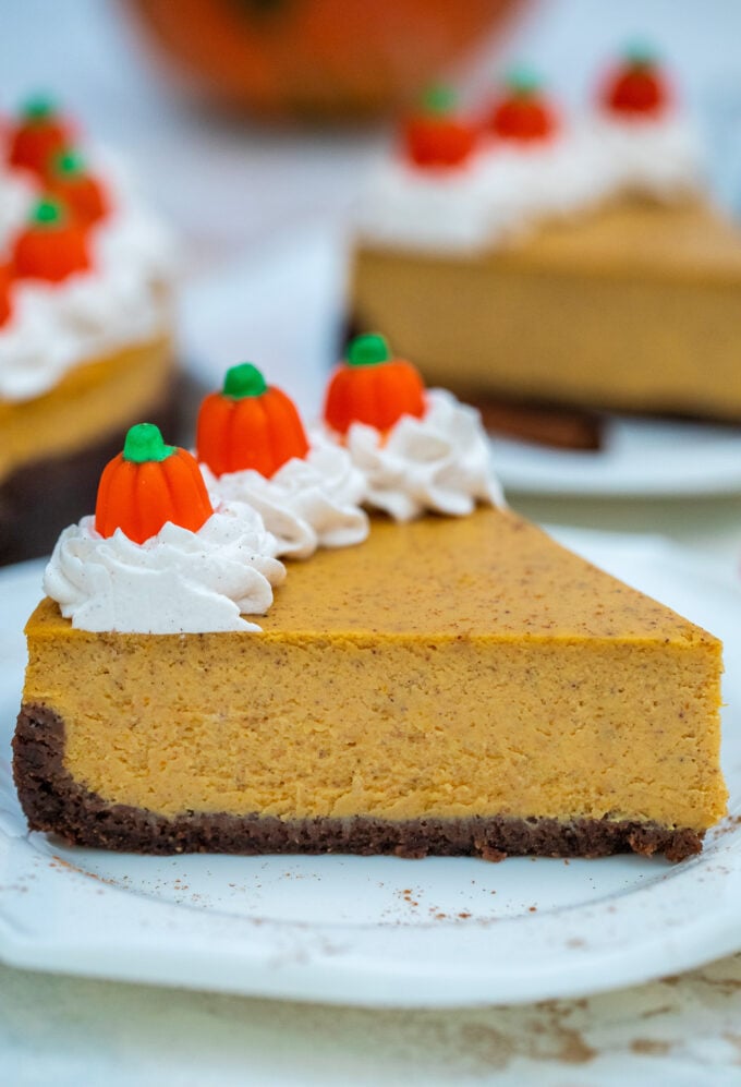 a slice of pumpkin cheesecake topped with whipped cream on a plate