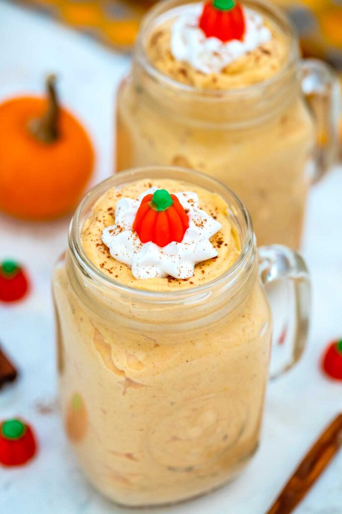 Homemade pumpkin mousse made with pumpkin puree, heavy cream, and topped with mini pumpkins and ground cinnamon in jars