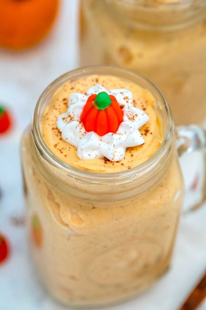 Pumpkin mousse dessert topped with ground cinnamon and whipped cream in a jar
