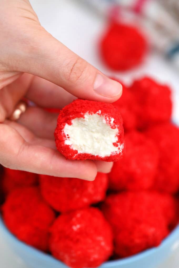 A hand holding creamy Red Velvet Cheesecake Bites