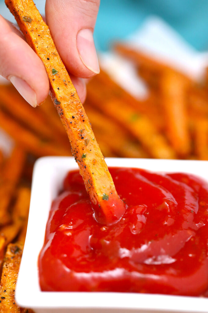 Crispy sweet potato wedge dipped in ketchup. 