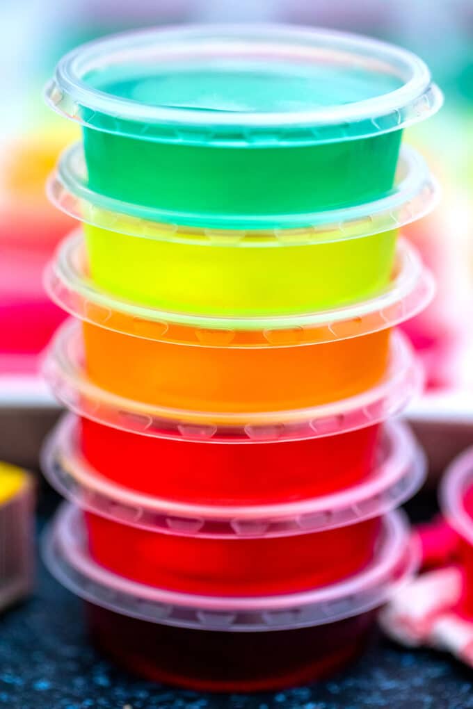 Different colored jello shots in small plastic cups.
