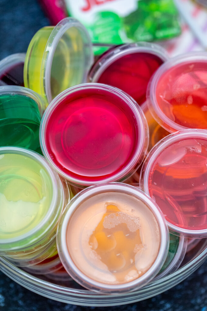 Bowls of liquid gelatine in different colors packed in small plastic cups.