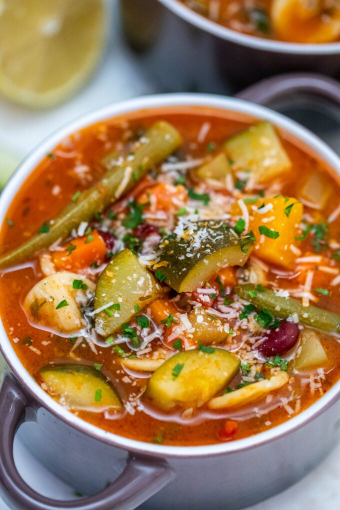 ¡La sopa de Minestrone Vegetariana de cocción lenta podría ser su salvavidas de cena de entre semana ocupada! Es saludable, abundante y la manera perfecta de usar las verduras sobrantes. #slowcooker #crockpotrecipes #souprecipes #ministrone #sweetandsavorymeals