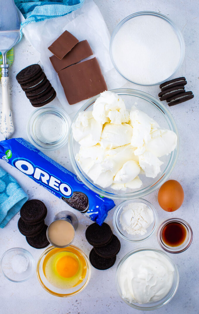 Overhead shot of Bailey's cheesecake ingredients in bowls on a white surface.