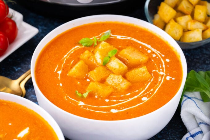 A bowl of creamy Instant Pot tomato bisque topped with croutons and basil.