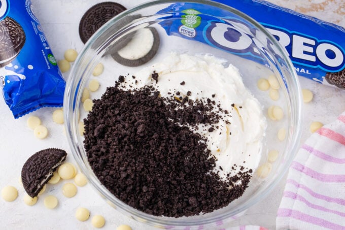 Mixing Oreo crumbs and cream cheese in a bowl.