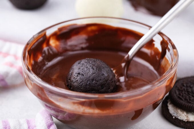 Dipping Oreo balls in melted chocolate.