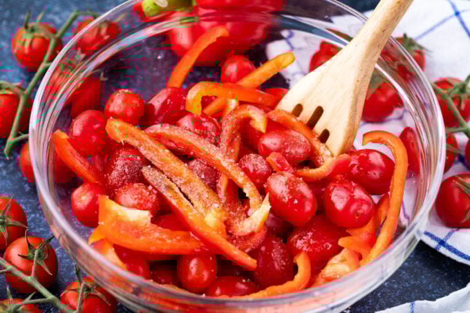 Mixing cherry tomatoes and bell peppers.