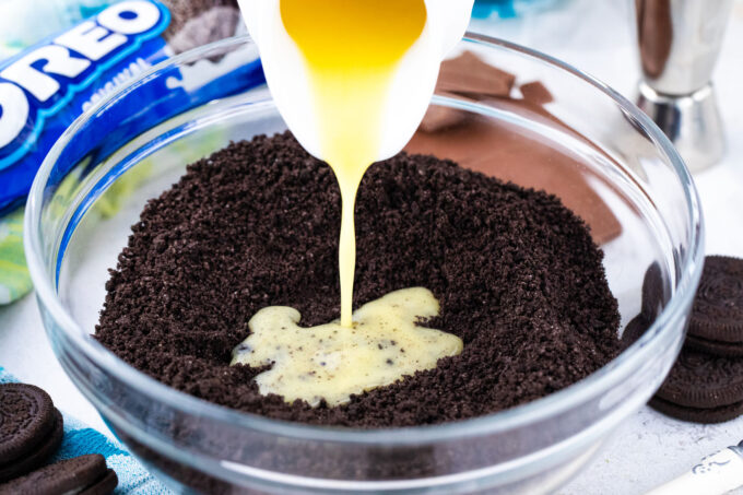 Adding melted butter to Oreo cookie crumbs.