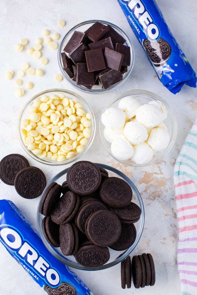 Overhead shot of no bake Oreo balls ingredients in bowls on a white surface.