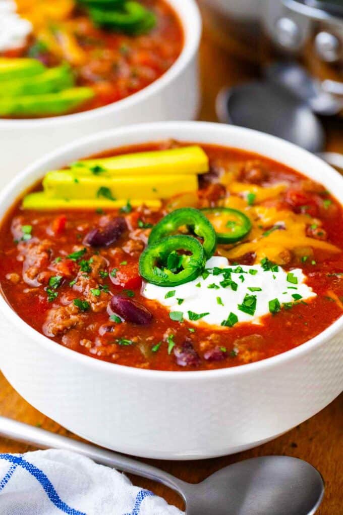 a bowl of homemade Wendy's chili topped with avocado, cheese, spur cream, and jalapenos