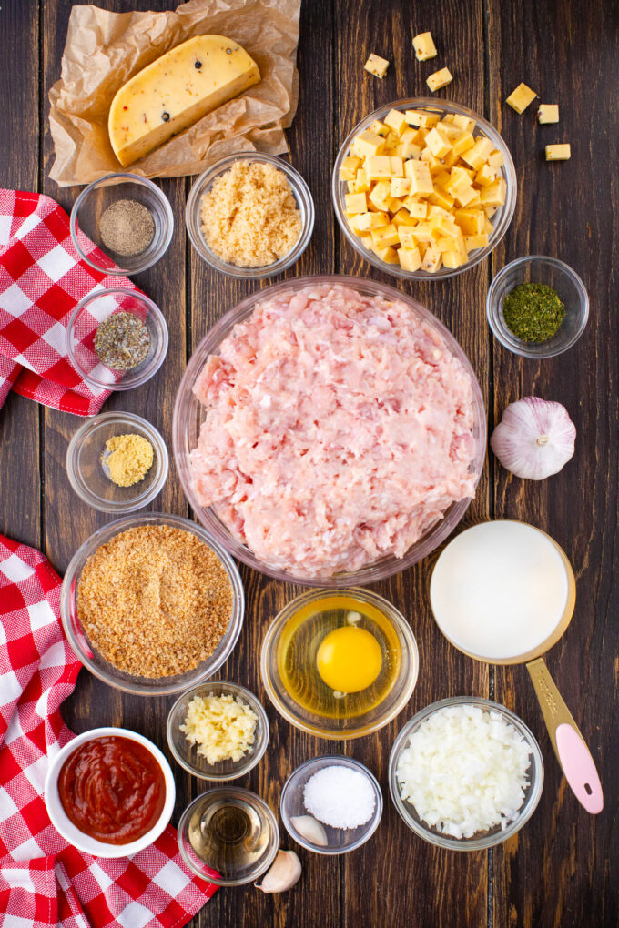 Overhead shot of turkey meatloaf with Pepper Jack cheese ingredients in bowls on a wooden table.