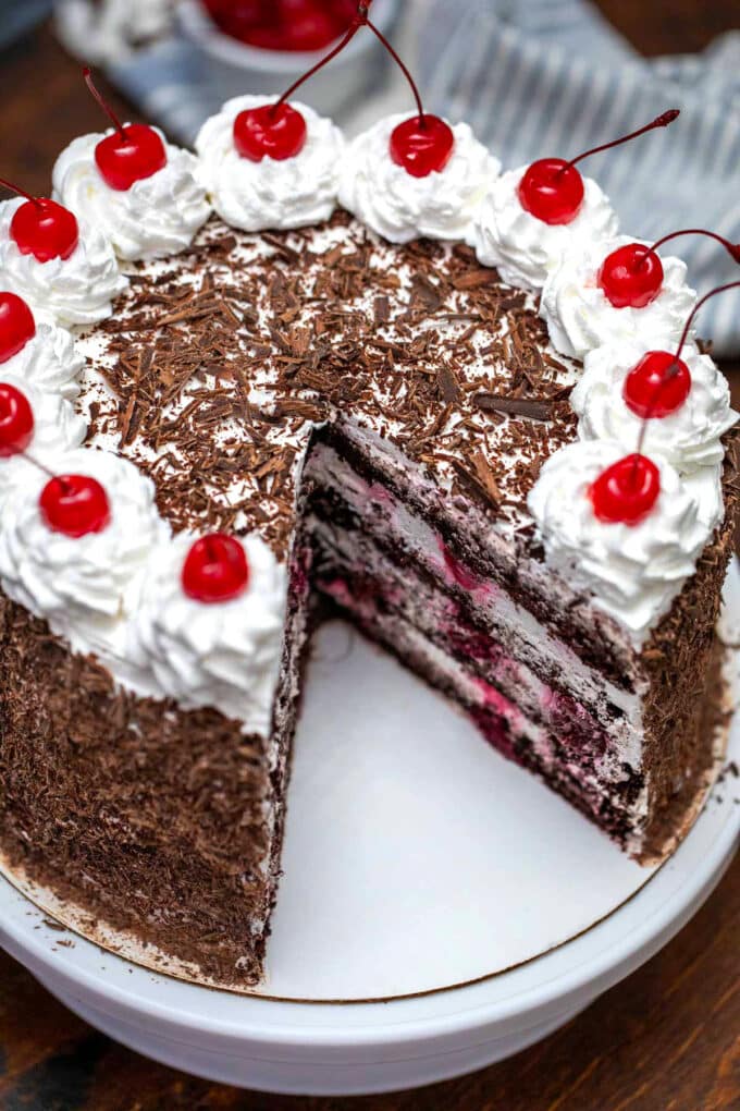 photo of sliced Black Forest cake with whipped cream, cherries and chocolate shavings