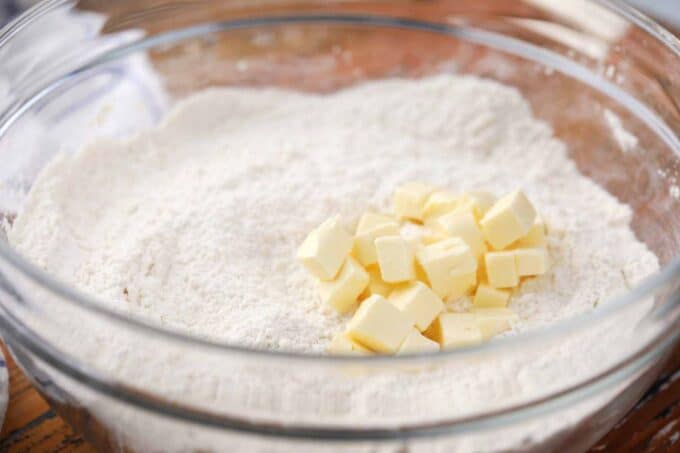 adding diced butter to a bowl of flour