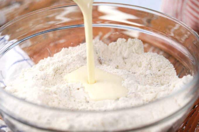 pouring buttermilk into a bowl with flour