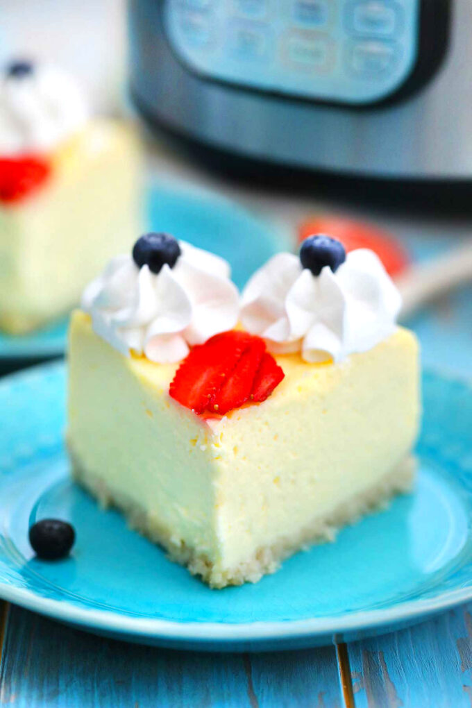 image of sliced instant pot keto cheesecake with berries and whipped cream