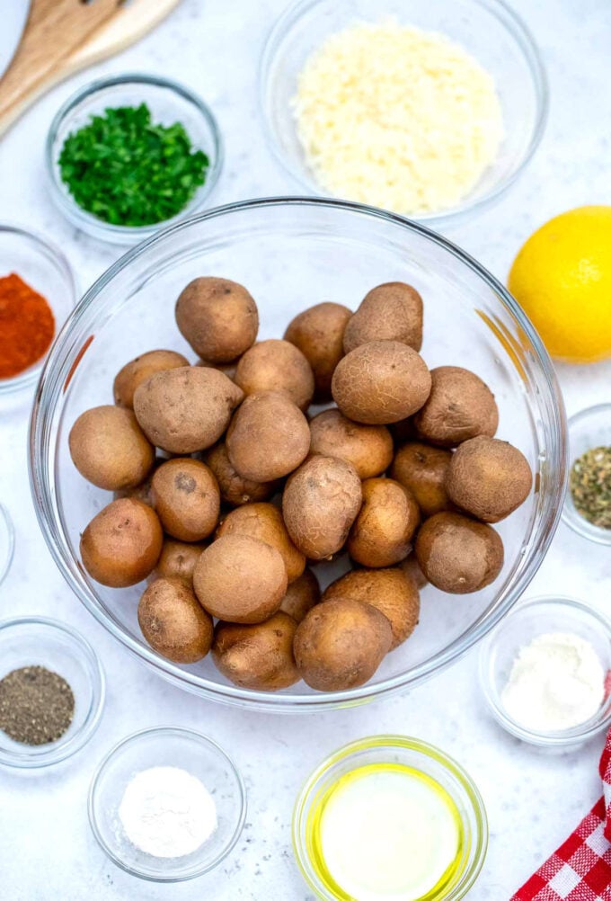 Baby potatoes in a large bowl along with seasoning ingredients for roasting