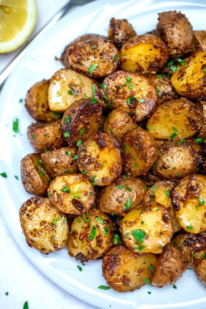 Crispy roasted air fryer potatoes garnished with chopped parsley on a white plate