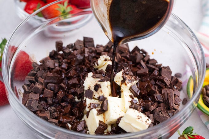 Pouring coffee over chopped chocolate and butter in a bowl.