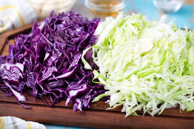 Shredded green and purple cabbage on a cutting board.