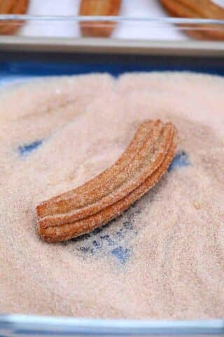rolling churros in cinnamon sugar