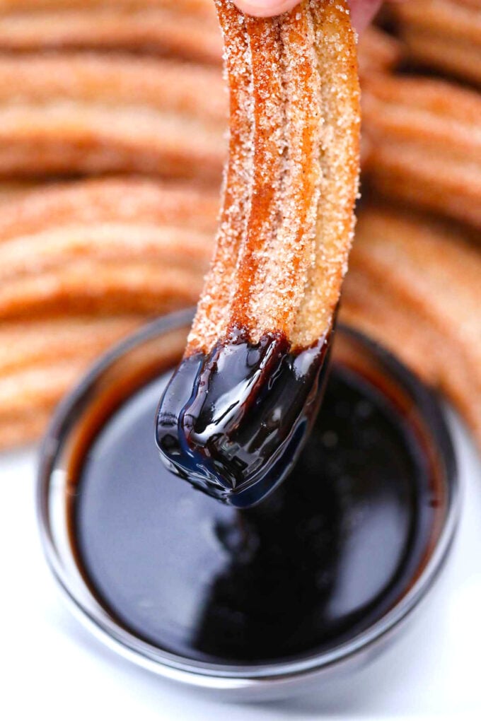 image of a churro dipped in chocolate sauce