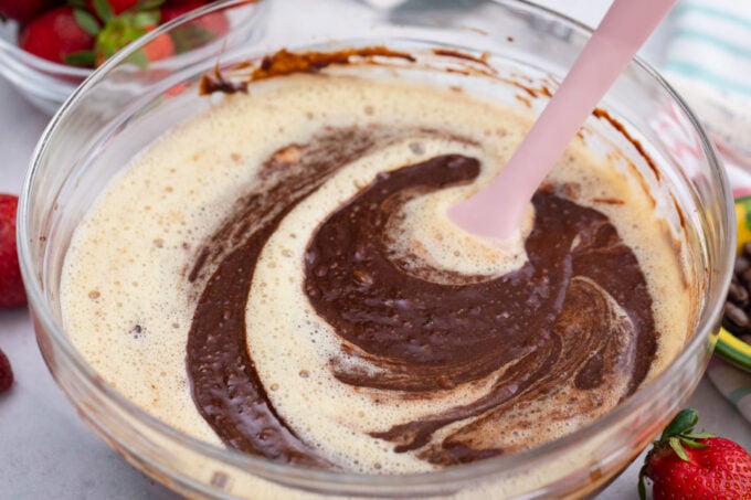 Stirring chocolate flourless cake batter in a bowl.