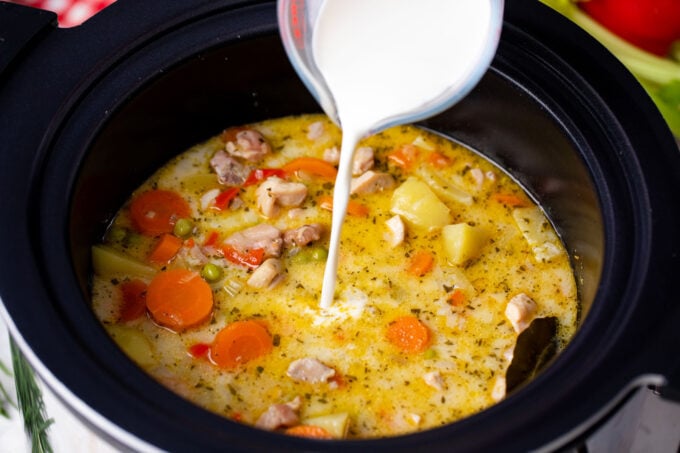 Pouring cream into slow cooker chicken stew.