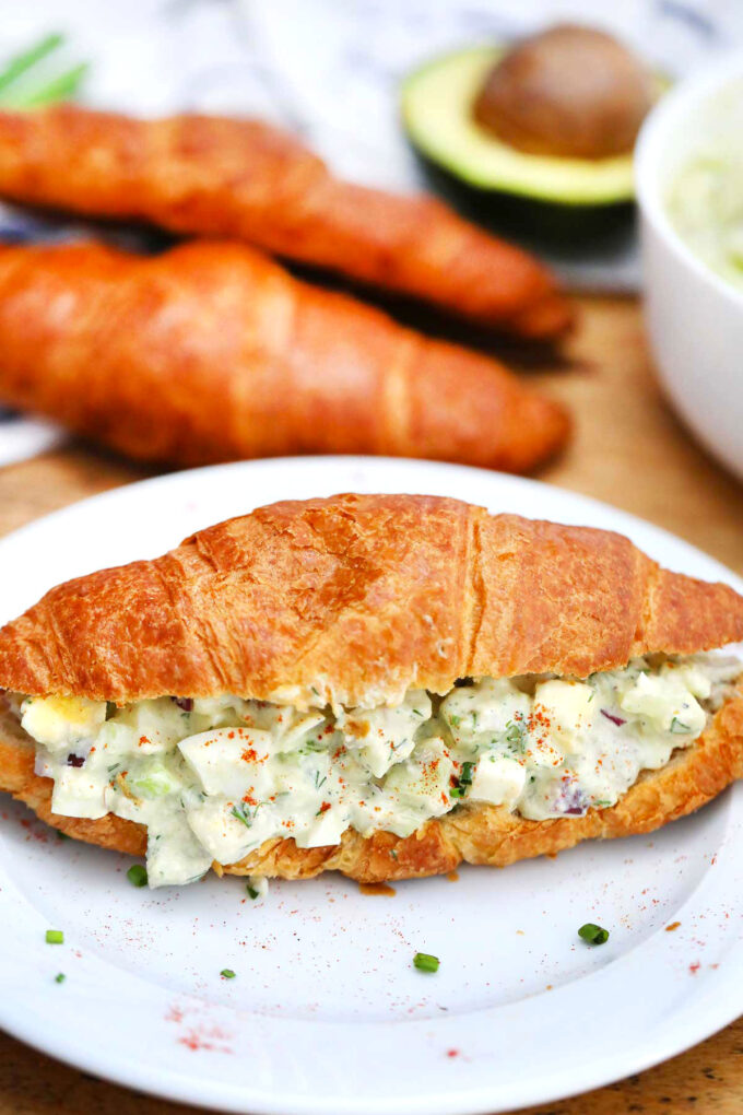 Photo of egg salad made with avocado on a croissant.