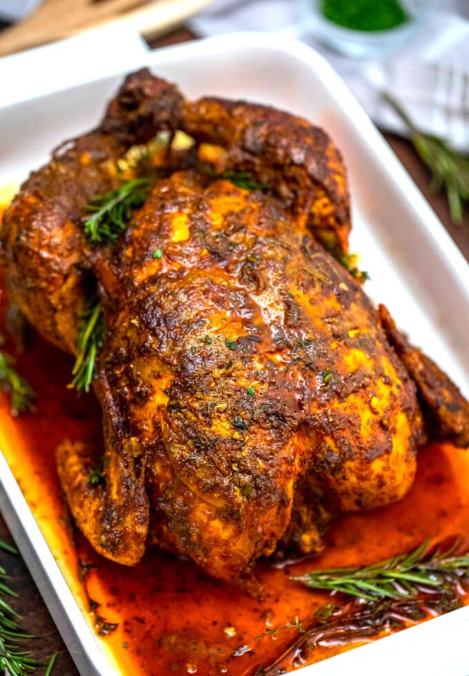 garlic herb butter roasted chicken in a baking pan with fresh rosemary