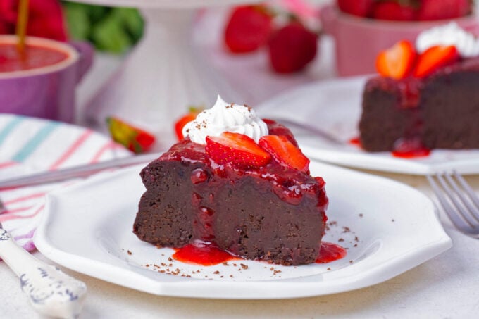 A slice of low-carb chocolate flourless cake topped with strawberry sauce.